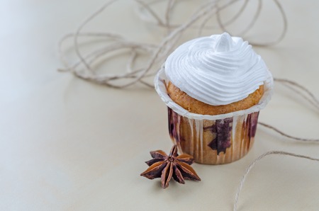 Cake with cream on wooden board decorated with dried cloves and twineの写真素材
