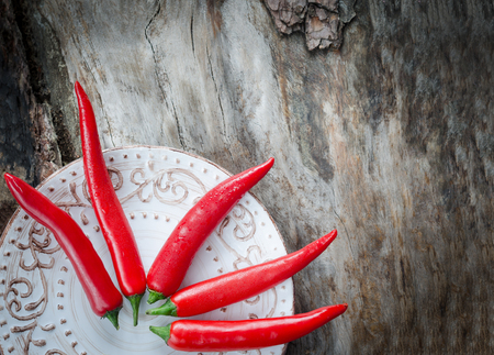 Red chillies on aged wood background. Vintage plateの写真素材