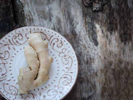 Ginger root on a vintage plate on a background of weathered wood