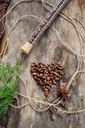 Unshelled pine nuts in form of heart on aged wood.の写真素材