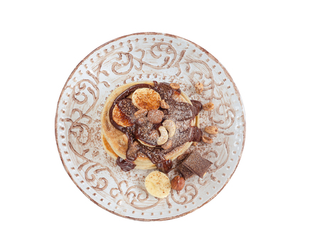 Stack of hot pancakes with nuts, bananas and chocolate syrup. Isolated.の写真素材