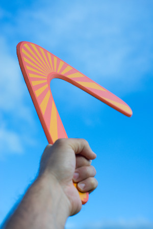 Boomerang in front of a blue sky in man handの写真素材