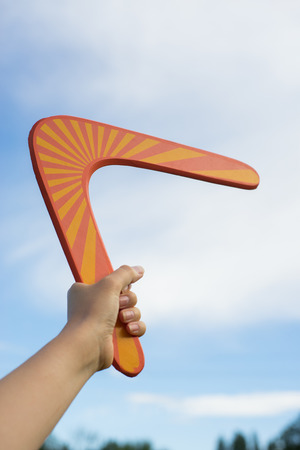 Boomerang in front of a blue sky in woman handの写真素材
