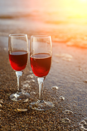 Two red wine glasses in front of the setting sunの写真素材