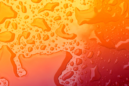 Water drops on red background with red to yellow gradientの写真素材
