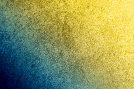 A textured vintage stucco background with a dark blue to golden yellow gradient.の写真素材