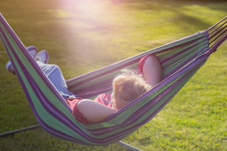 beautiful girl resting in a hammock at sunset.の写真素材
