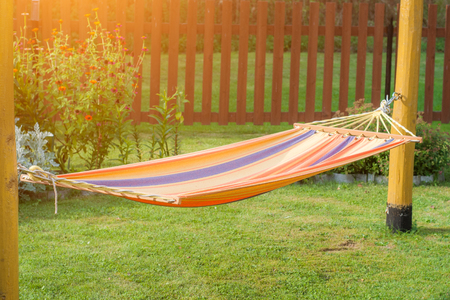 A multicolored hammock hangs on two poles. Sunlightの写真素材