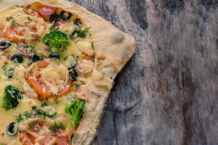Tasty pizza with olives and broccoli on an old wooden log.の写真素材