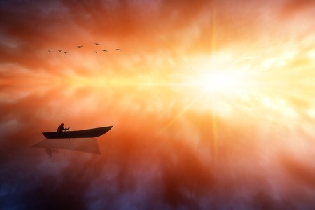 Boat With a Man on the Sea Water. Fiery Sea Sunset With Seagulls And Sun Rays.の写真素材