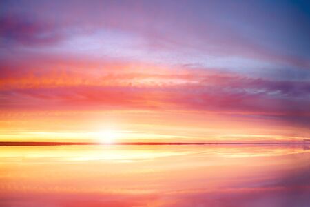Sunset at the sea, beautiful cloud and sky. Calm sea with sunset sun through. Meditation ocean and sky background. Tranquil seascape. Horizon over the water.の写真素材