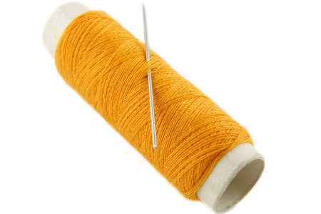 Orange thread bobbin with needle on white backgroundの写真素材