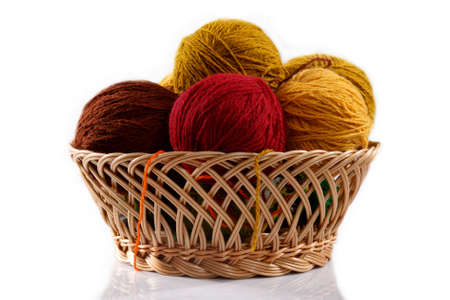 wicker basket with colorful balls of wool on a white background の写真素材