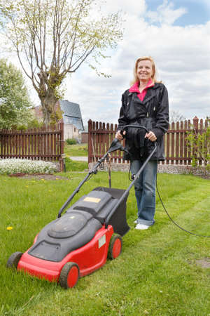 Woman mowing a garden with an electric lawn mowerの写真素材