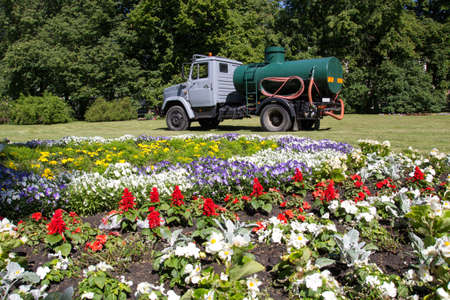 City park with a large flower bed and watering carの写真素材