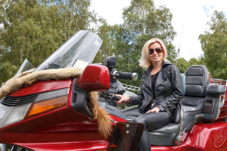 Woman dressed leather clothes on a big red motorcycleの写真素材