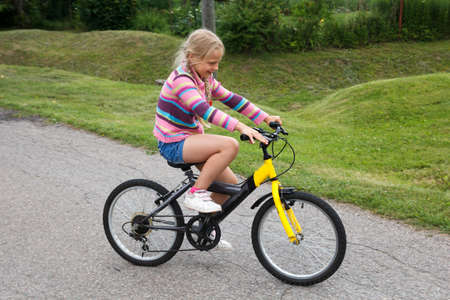 little girl learning to ride a bicycle on empty streetの写真素材