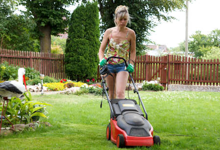Woman cuts the grass with an electric lawn mowerの写真素材