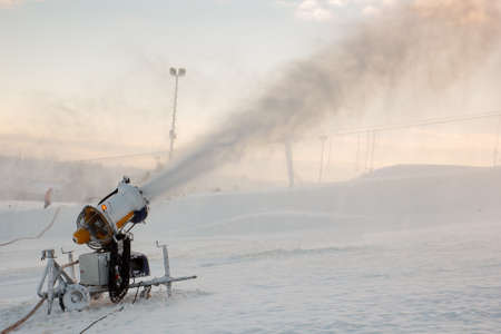 A snow blowing muchine being used to spray snowの写真素材