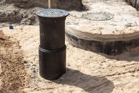 A road construction site covered in sand with a sewer hole