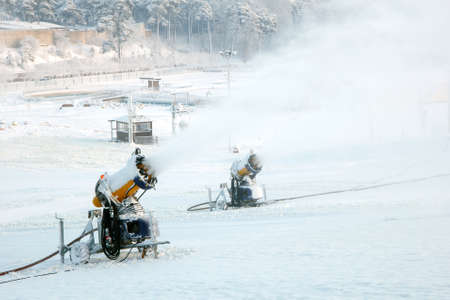 A pair of snow blowers blowing snow on a mountainの写真素材