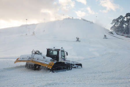 A heavy snow moving vehicle by a snowy hillの写真素材