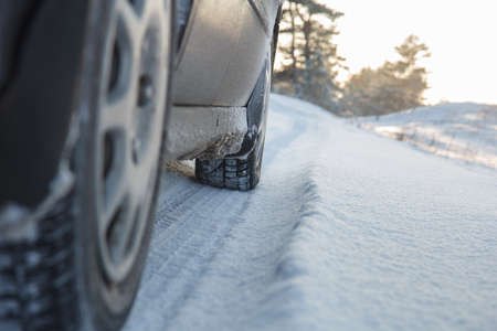 Car wheels leaving tracks on a snowy road