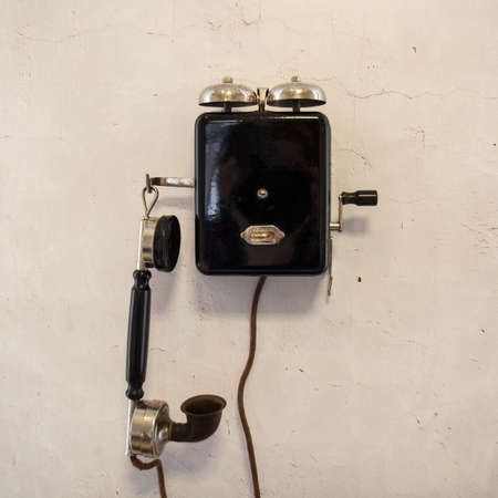 Old dialschool phone by a gray wallの写真素材