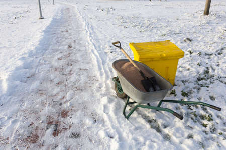 wheelbarrow with sand on the icy sidewalkの写真素材
