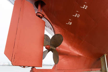 a rusty red fishing boat propeller in dock