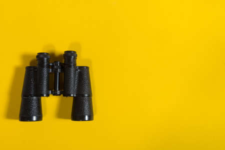 Black metalic binoculars on a yellow backgroundの写真素材