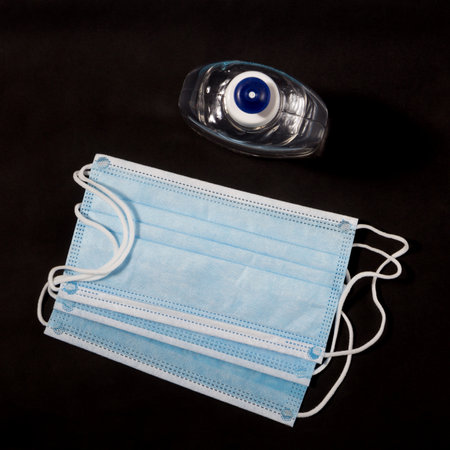 Alcohol gel hand sanitizer and disposable hygienic mask on black backgroundの写真素材