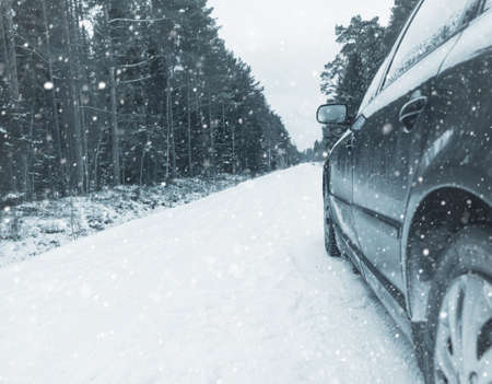 Winter Driving. Driving car through forest by small snowy road.