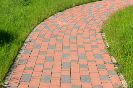 brick paved sidewalk through a green grass