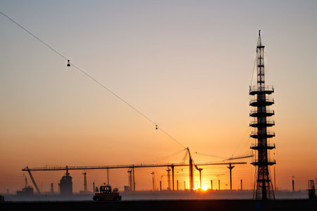 silhouette of an engineer at a construction Construction worker at sunset with tower cranes in theの素材