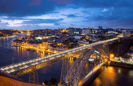 View of the historic city of Porto, Portugal with the Dom Luiz bridge at dusk.の写真素材