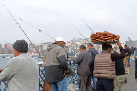 Istanbul, Turkey - October 23, 2018: City scene. Peddler bagels between fishermen on the Galata bridge across the Golden Horn Bayのeditorial素材