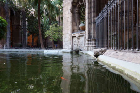 Barcelona, Spain - October 14, 2017. Inside the Cloister of Saint Lucia. The pool with animal shaped fountains. Red fish swims in clear greenish water. Pacificationのeditorial素材