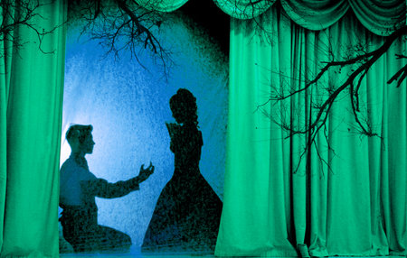 A man and woman in theatrical costumes in the theater of shadows on the stage with red curtains. Love in the shadows theater. Red curtain of opera, cinema or theater stage drapes.の写真素材