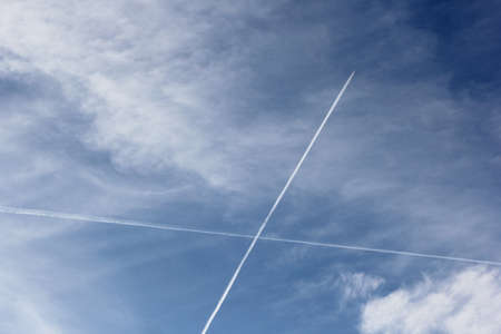 Airplane flies leaving contrail trace on blue sky. Cross in the sky