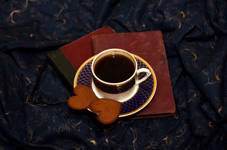 Coffee mug and two gingerbread hearth on the night blue background. The concept of love and...