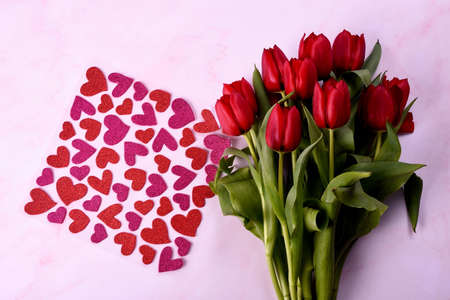 Red tulips bouquet and red hearts on a pink background. Valentine's Day, Woman's Day and Mother's Day concept. View from the topの写真素材