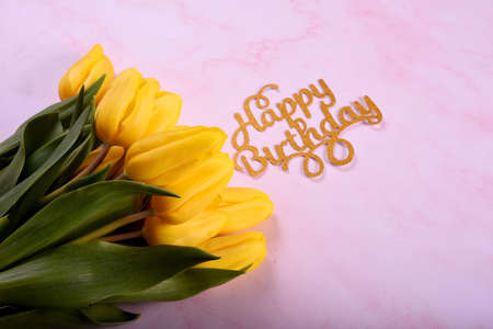 Bouquet of yellow tulips on a pink background and the text Happy Birthday. Happy Birthday Greeting...