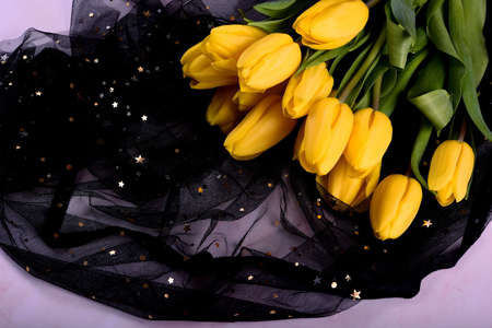 yellow tulip bouquet and a black cloth with small stars on a pink background