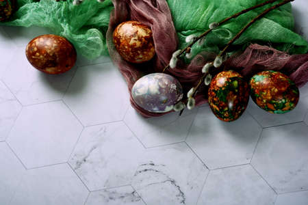 Naturally painted Easter eggs on a light background, decorated with green and brown gauze cloth and...