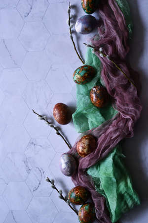 Naturally painted Easter eggs on a light background, decorated with green and brown gauze cloth and willow branches, Easter egg coloring with natural materials, Copy spaceの写真素材