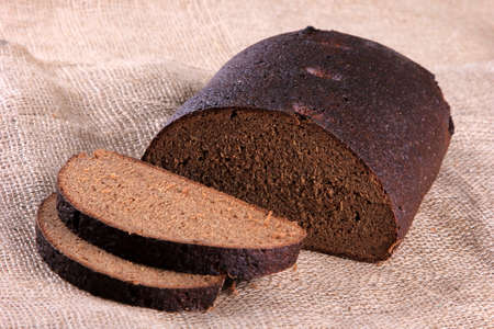 Fresh sliced rye bread loaf isolated on the wooden table and napkins