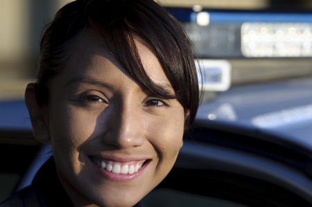 a happy female police officer standing next to her patrol unit. の写真素材