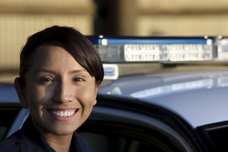 a happy female police officer standing next to her patrol unit. の写真素材