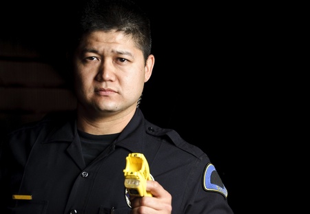 a male police officer pointing his taser gun at night. 